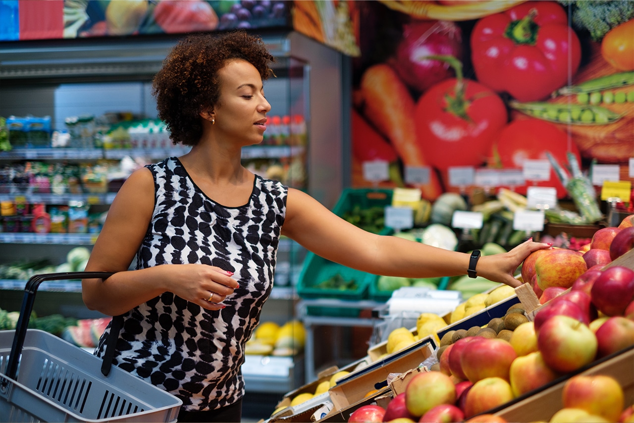 Woman shopping in the produce section of a grocery store in order to eat healthy